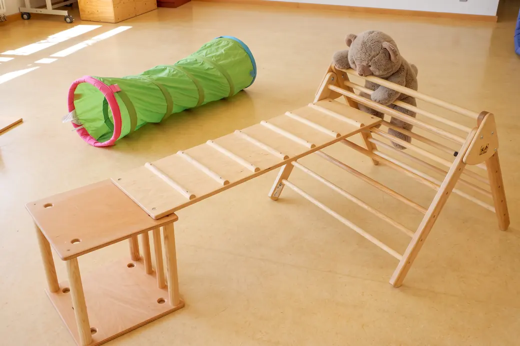 Bewegungslandschaft aus Holz mit Krabbeltunnel und Teddy